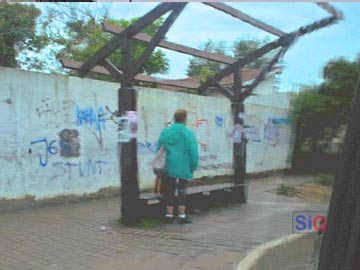 Sin techo: una seora espera el colectivo bajo la lluvia, en paseo 107